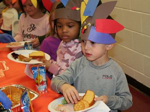picture of students lined up at table receiving Thanksgiving feast food on plates