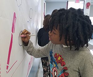 picture of student signing No One Eats Alone pledge