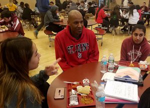 picture of Family Outreach Coordinator talking with students in the school cafeteria