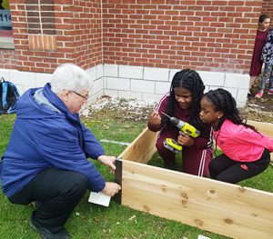 picture of staff volunteer helping students build garden bed