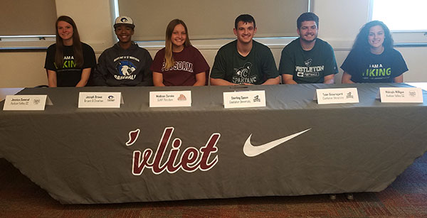 group picture of six student athletes seated at table with WaterVliet athletic banner