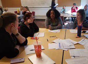 picture of teachers seated at desks engaged in conversation