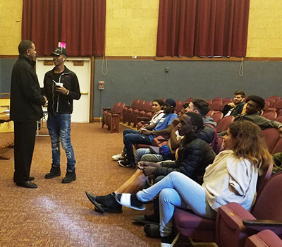 picture of student shaking hands with Albany Patroon head coach with seated audience members in the background  