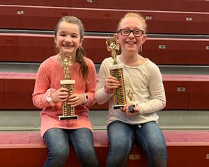 picture of spelling bee champion and runner up holding trophies and smiling