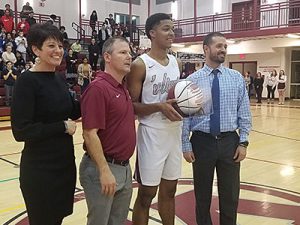 picture of coach, principal and superintendent presenting player with commemorative basketball