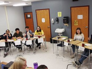 picture of four varsity Masterminds team members seated at desks in classroom competing against Rensselaer Masterminds team 