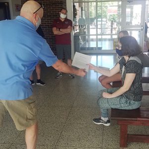 picture of science teacher handing science award scholarship to student seated on bench as high school principal and assistant superintendent stand nearby