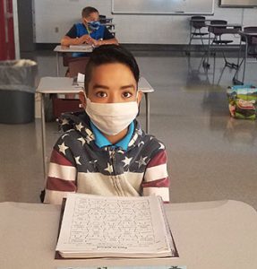 picture of grade 6 student wearing face mask seated at desk looking directly at camera