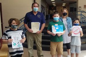 picture of Elks representative standing alongside student poster contest winners and the art teacher in the school lobby