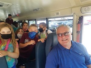picture of bus driver retiree surrounded by students on final bus run