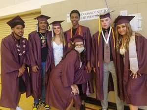 picture of seven graduates standing together in a group dressed in caps and gowns