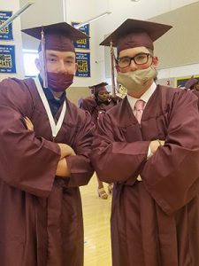 picture of two graduates with arms folded looking at camera with serious expression