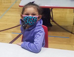 picture of prekindergarten student with mask sitting at desk facing forward
