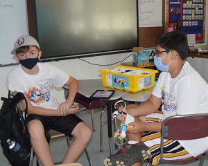 picture of two students seated at desk working with Lego robot kit