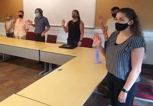 picture of new teachers standing with hands raised taking oath