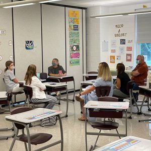 picture of educators seated in classroom a circle formation talking