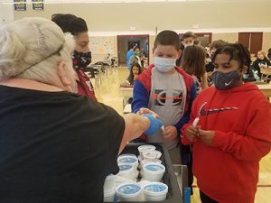 picture of cafeteria worker handing out ice cream to two students in line