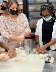 picture of teacher and student standing at kitchen counter kneading dough