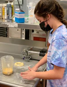 picture of student working at counter to roll dough into a bagel