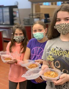 picture of three students holding containers filled with baked bagels