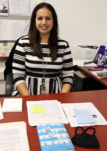 picture of new director of curriculum and instruction seated at desk, smiling at camera