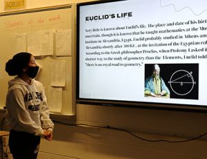 picture of student standing in front of whiteboard presenting math project