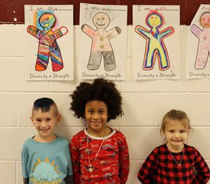 picture of three students standing in hallway underneath their self-portraits