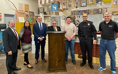 picture of student standing behind podium with Watervliet mayor flanked by police chief, superintendent of schools, Career and Technical School principal, city manager and Career and Technical School teacher