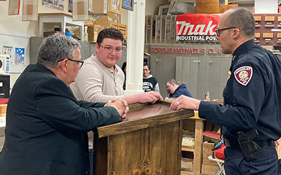 picture of student standing with Watervliet Mayor and Police Chief at the podium he built