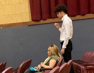 picture of student with hand raised pledging the oath to uphold the requirements of membership in National Honor Society