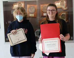 picture of the two scholarship winners looking at camera holding their certificates