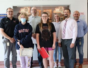 picture of two scholarship winners standing next to the high school principal and in front of the superintendent, the science department chairperson, and two school guidance counselors. All facing forward and smiling at camera.