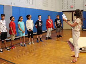 Standing in the gym, the principal shares information with student recipients about physical education leadership awards