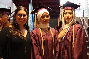 Two students stand with their teacher all smiling at camera.