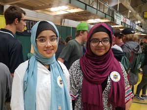 Two students standing together smiling at camera with Career Jam activities in the background.