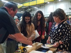 Two students visit a Career and Technical Education booth and participate in hands-on activity demonstration.