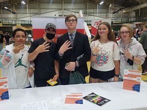 Five students standing together smiling at camera with Career Jam activities in the background.