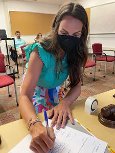 Kelly Webster is appointed assistant superintendent at board of education organizational meeting. She is shown signing a contract for the new position.