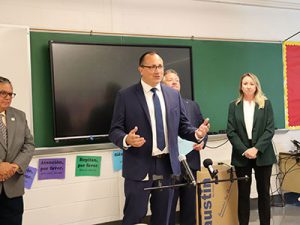 Superintendent Donald Stevens speaks into microphone at front of the classroom. County Executive Dan McCoy and President of Austin Air Systems Lauren McMillan stand in the background..