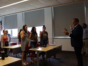 Dr. Stevens stands at the front of the room leading new staff members in the oath of office.