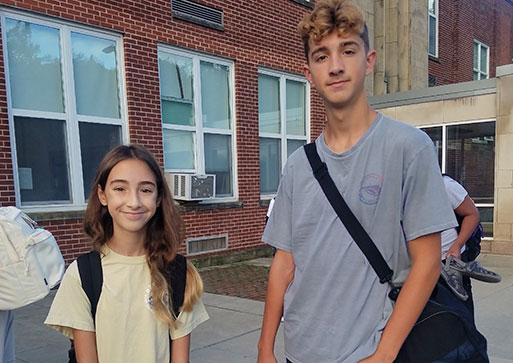 Two students standing at the entrance to the junior senior high school looking at the camera and smiling.