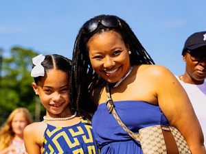 Parent and child stand close together smiling at camera.