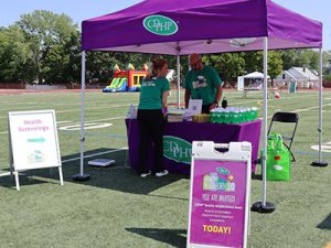 CDPHP staffers set up health screening booth on athletic field for welcome back event. 