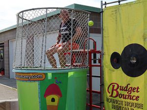 superintendent seated on dunk tank bench watches as ball is thrown at the target.