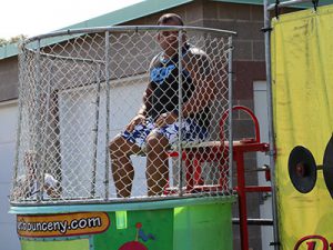 School resource officer sits on dunk tank bench looking at crowd.