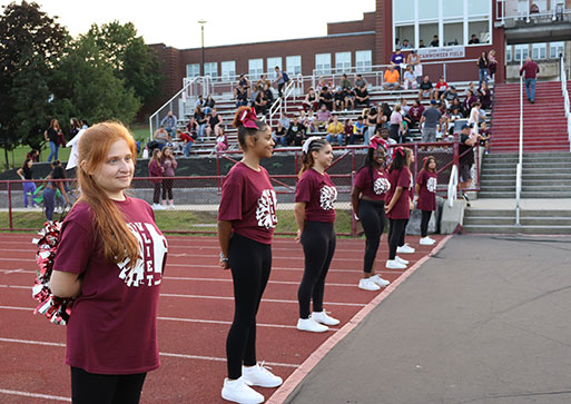 Cheer squad lines up to greet football players on the field.