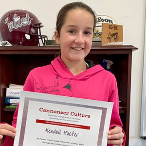 grade 7 student smiling at camera holding Cannoneer Culture certificate for Being Proud