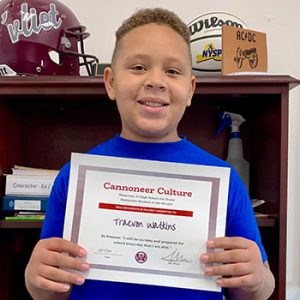 grade 6 student smiling at camera holding Cannoneer Culture certificate for Being Present 