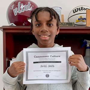 grade 7 student smiling at camera holding Cannoneer Culture certificate for Being Productive