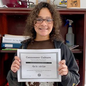 grade 6 student smiling at camera holding Cannoneer Culture certificate for Being Productive